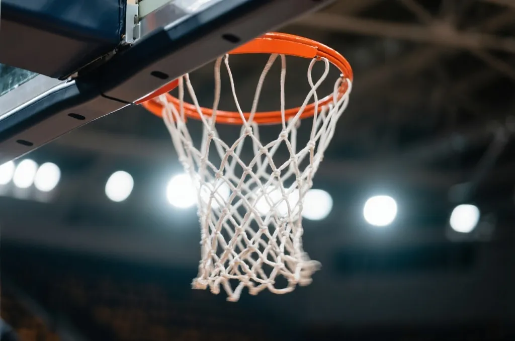 Basketball hoop net swishing with stadium lights in the background